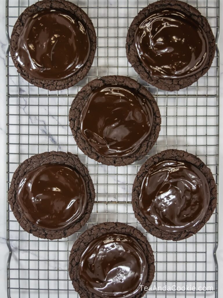 A wire rack of chocolate brownie cookies topped with chocolate ganache.