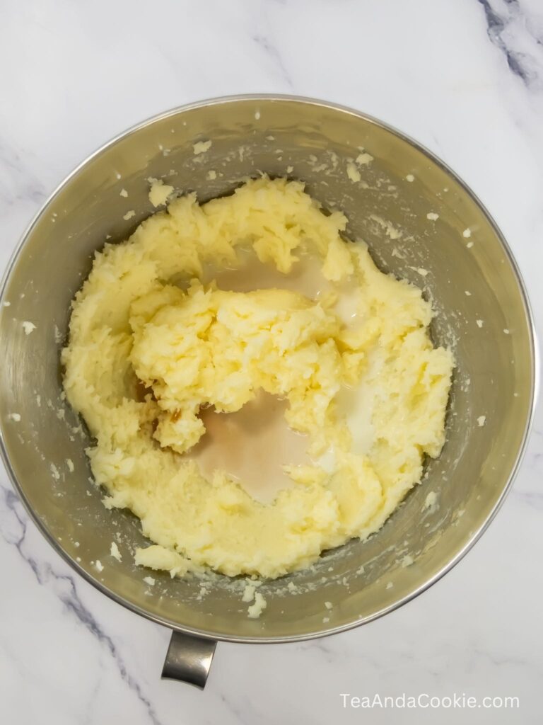 A bowl of creamed butter and sugar with milk and vanilla extract added