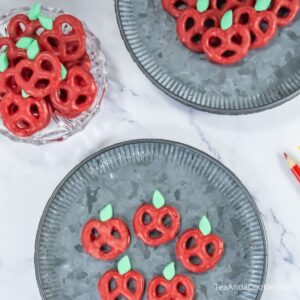 A plate of mini pretzel twists coated in red chocolate and decorated to look like an apple