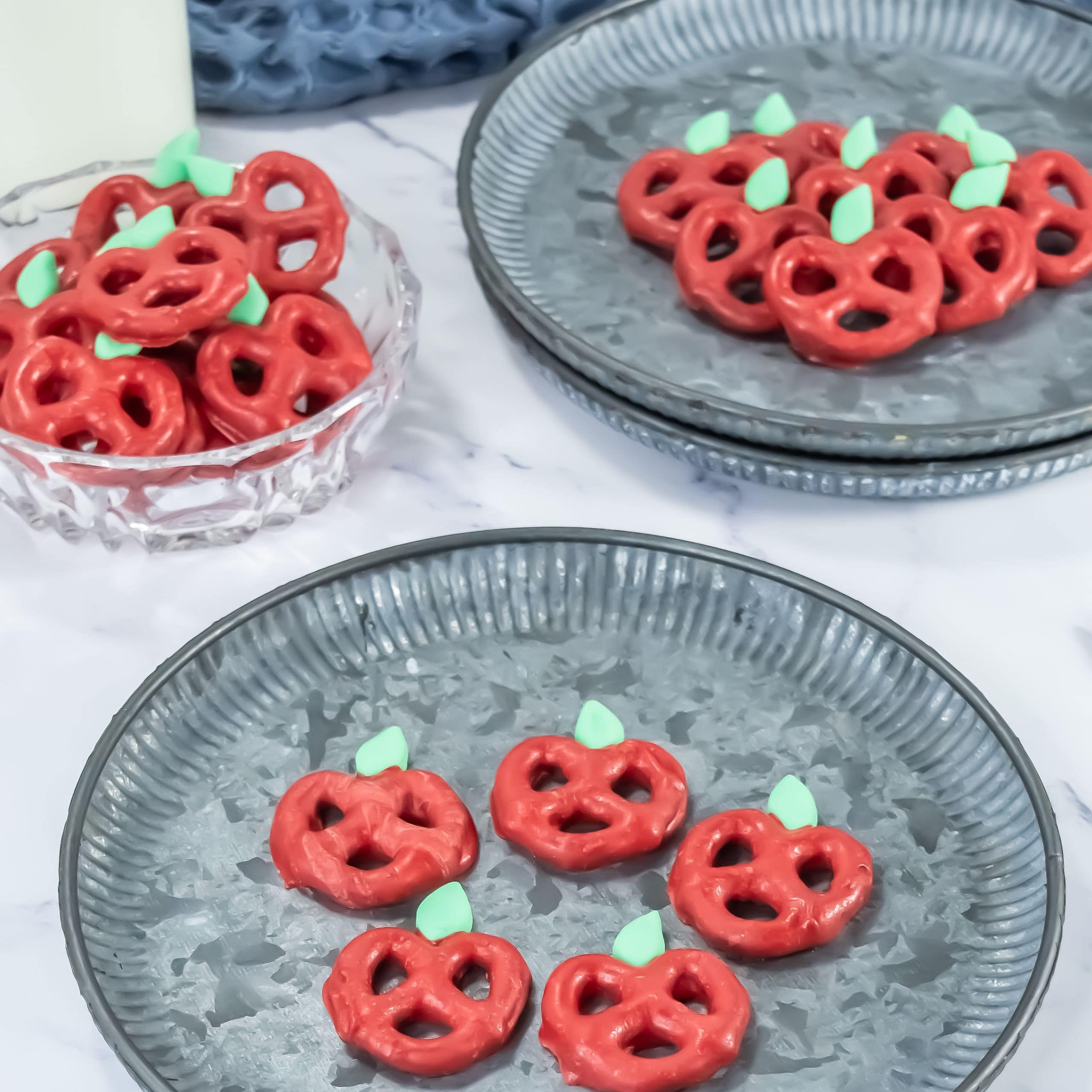 A plate of mini pretzel twists coated in red chocolate and decorated to look like an apple
