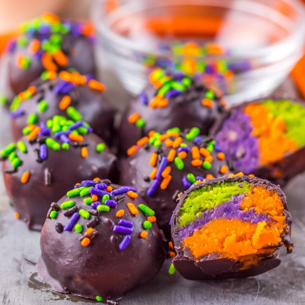 Chocolate balls broken in half to reveal a colorful inside with green, orange, and purple colors