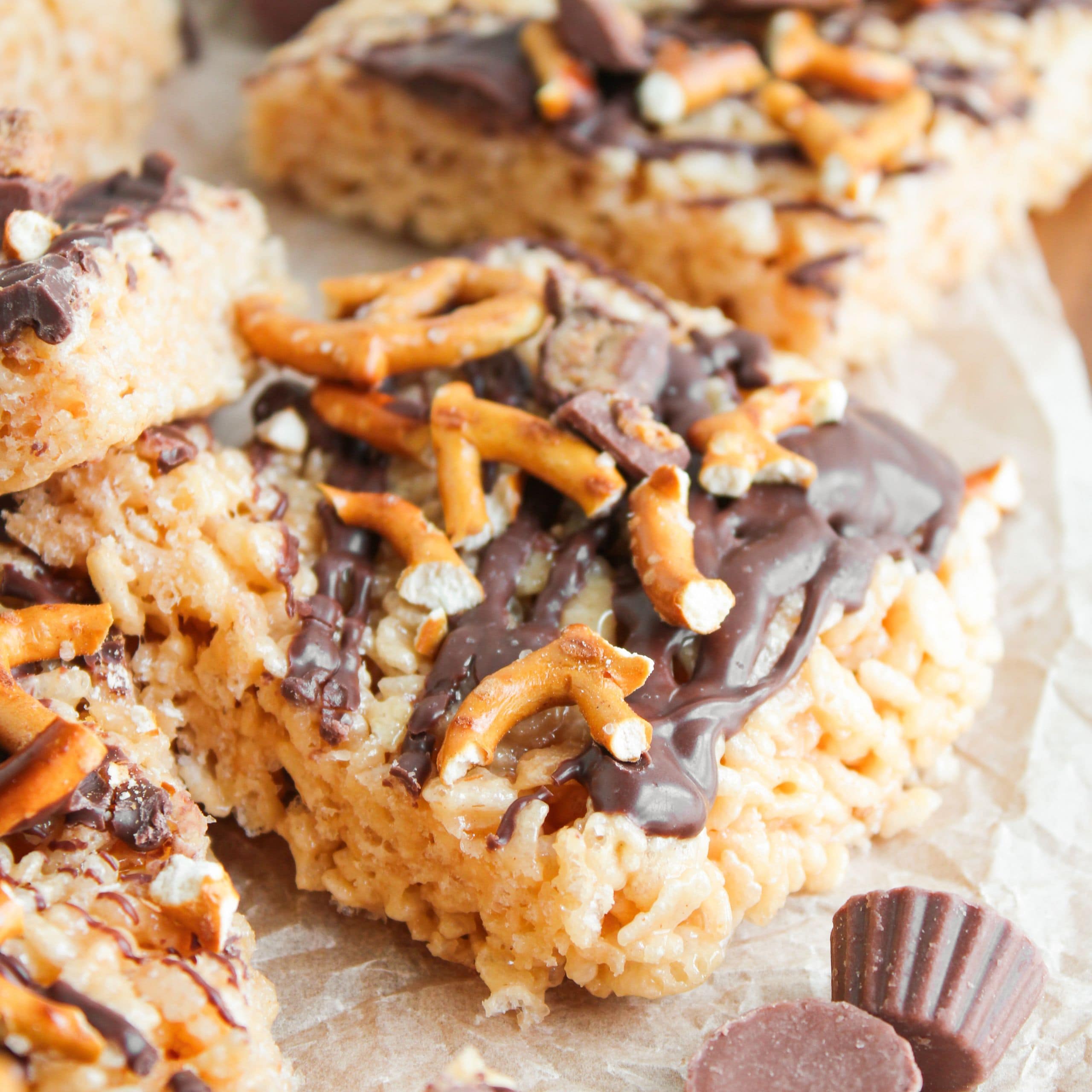 A closeup picture of rice krispies with peanut butter and chocolate topped with pretzels and mini Reese's