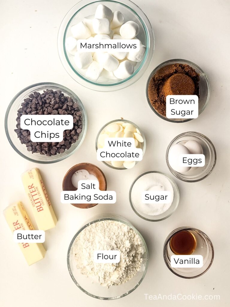 Top-down view of labeled baking ingredients including marshmallows, chocolate chips, white chocolate, brown sugar, eggs, sugar, vanilla, flour, butter, salt, and baking soda.