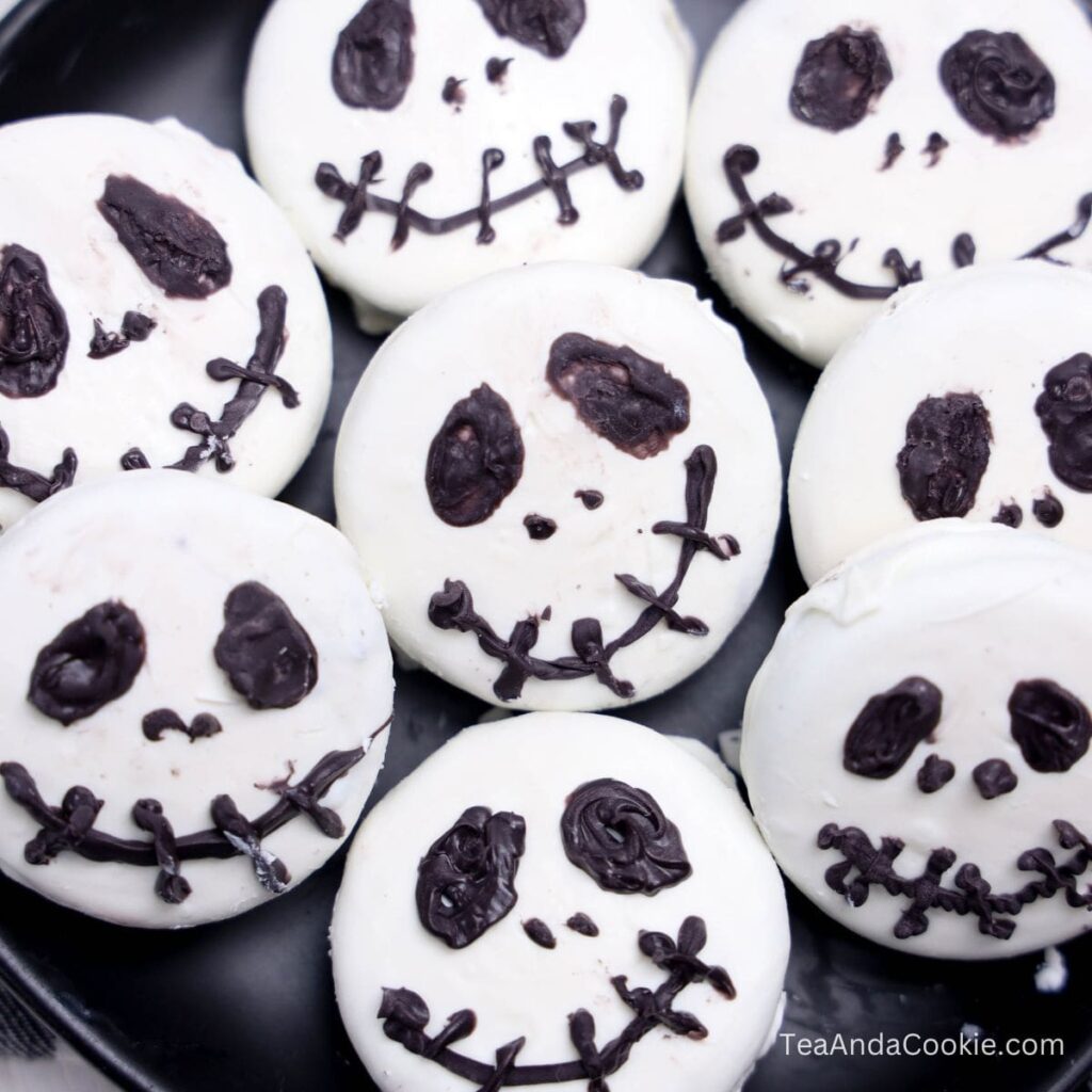 Easy Jack Skellington Oreos. A plate of round cookies decorated with white icing and black icing to resemble Jack Skellington faces.