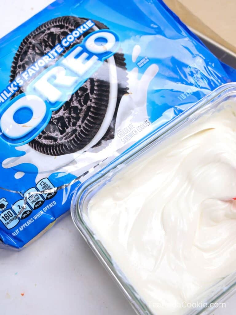 A package of Oreo cookies next to a glass dish filled with smooth, white cream or frosting.