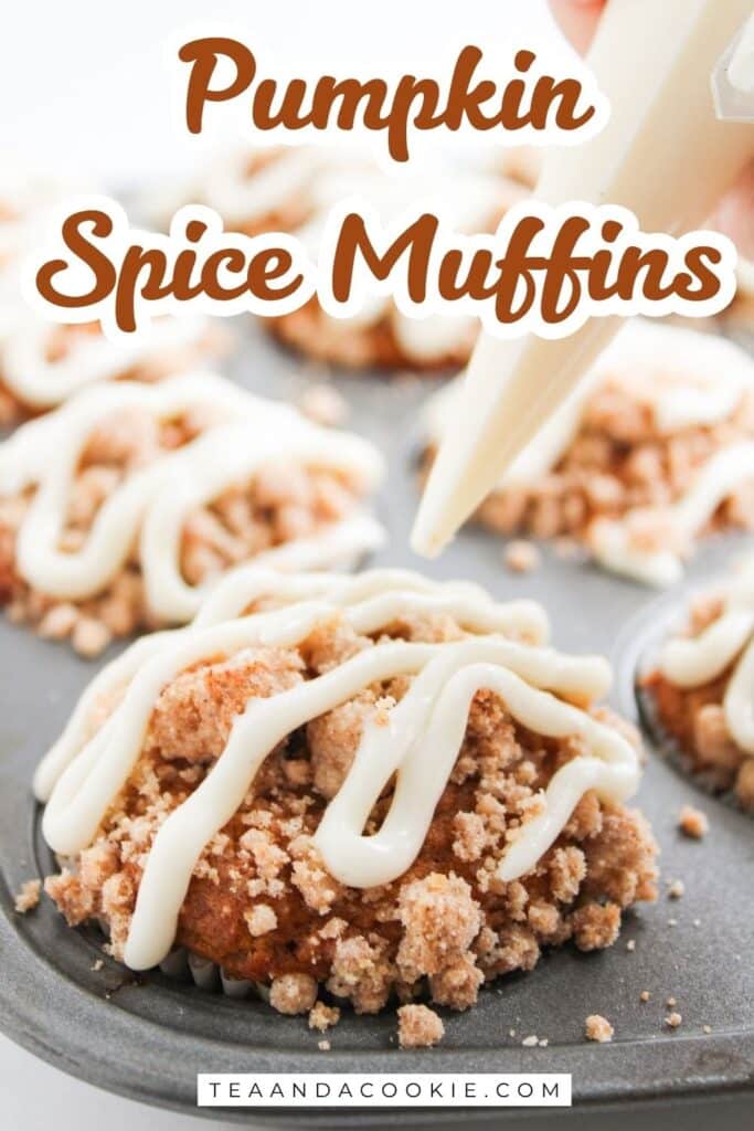 A hand pipes icing onto pumpkin spice muffins with crumb topping in a muffin tin. Text on image reads Pumpkin Spice Muffins and teaandacookie.com.
