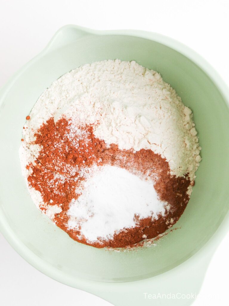 A mixing bowl containing flour, cocoa powder, baking soda, and salt, viewed from above.