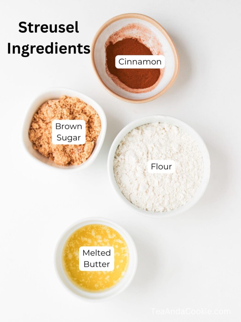 Four bowls containing streusel ingredients: cinnamon, brown sugar, flour, and melted butter, arranged on a white surface.